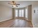 Bright bedroom featuring three windows with wooden floors and a ceiling fan at 623 Olmsted Park Pl # D, Charlotte, NC 28203