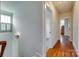Hallway with hardwood floors, sconce lighting, window with shutters, and open doorways at 750 Waterscape Ct, Rock Hill, SC 29730
