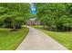 Long driveway leading to a beautiful two-story brick home, surrounded by lush trees and a well-manicured lawn at 763 Evans Manor Dr, Weddington, NC 28104