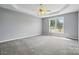 Spacious bedroom featuring a tray ceiling, neutral paint, carpet floors, and large window with backyard view at 924 Secrest Hill Dr, Monroe, NC 28110