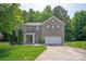 Charming two-story brick home with an attached two-car garage, manicured lawn, and lush landscaping at 10044 Markus Dr, Mint Hill, NC 28227