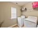 Functional laundry room features a washer, dryer, shelving, and a window for natural light at 10044 Markus Dr, Mint Hill, NC 28227