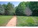 A winding dirt path leads through the lush green grass and trees in the backyard of the property at 10044 Markus Dr, Mint Hill, NC 28227