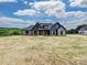 A striking home featuring dark siding, stone accents, and a timber-framed porch stands on a generously sized lot at 1172 Springlake Rd, York, SC 29745