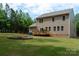 Expansive backyard view with a deck, fire pit, lush lawn, and a two-story tan home exterior at 13025 Cinnamon Fern Ln, Charlotte, NC 28227