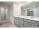 Bright bathroom featuring a double vanity with gray cabinets and a large mirror at 13025 Cinnamon Fern Ln, Charlotte, NC 28227