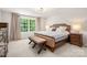 Primary bedroom with large window, neutral carpet, bench seat, and bedside tables at 13025 Cinnamon Fern Ln, Charlotte, NC 28227