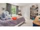 Well-lit bedroom with a colorful bed, dark curtains, and bookshelves at 13025 Cinnamon Fern Ln, Charlotte, NC 28227