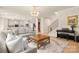 Bright living room features modern light fixture, wood floors, stairs, and flows into eat-in kitchen at 13025 Cinnamon Fern Ln, Charlotte, NC 28227