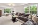 Spacious living room featuring a large leather couch, big bright windows, and a coffee table at 13025 Cinnamon Fern Ln, Charlotte, NC 28227