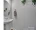 Stylish powder room featuring a pedestal sink, round mirror, and decorative plants at 149 Briana Marie Way, Indian Trail, NC 28079