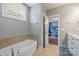 Bathroom featuring white cabinets, ceramic tile floor, soaking tub, and natural light at 1620 Arnold Dr, Charlotte, NC 28205