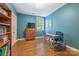 Blue office featuring desk, wooden floors, shelving with books, and window at 1620 Arnold Dr, Charlotte, NC 28205