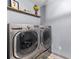 Laundry room showcasing a modern, front-loading washer and dryer set and floating shelves for storage at 1725 Mill Creek Sw Ln, Concord, NC 28025