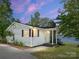 Charming single-story home with stone chimney, brown shutters, and lake views at sunset at 17835 Terryglass Ln, Charlotte, NC 28278