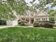 Inviting two-story home with lush landscaping, a front porch with rocking chairs, and attached two car garage at 2406 Tarleton Twins Ter, Charlotte, NC 28270