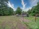 Expansive backyard with lush greenery, small wooden shed, and a charming fenced area for outdoor activities at 4636 Brown Creek Church Rd, Wadesboro, NC 28170