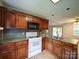 Functional kitchen featuring wooden cabinets, a white range, and a double stainless steel sink at 4636 Brown Creek Church Rd, Wadesboro, NC 28170