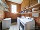 Laundry area with a washer, dryer, freezer, and wooden storage shelves at 4636 Brown Creek Church Rd, Wadesboro, NC 28170