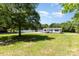 Serene view of a home with a large grassy area, complemented by mature trees and a white fence at 4750 Enochville Rd, Kannapolis, NC 28081