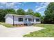 A well-maintained single-story home with gray siding, dark shutters, and a gravel driveway at 4750 Enochville Rd, Kannapolis, NC 28081
