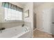 Relaxing bathroom featuring a large soaking tub under a window and a separate shower space at 5428 Colonial Garden Dr, Huntersville, NC 28078