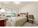 Cozy bedroom with a patterned bedspread, wooden furnishings, and soft natural light from the windows at 5428 Colonial Garden Dr, Huntersville, NC 28078