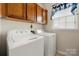 Functional laundry room featuring a washer, dryer, cabinetry, and natural light from the window at 5428 Colonial Garden Dr, Huntersville, NC 28078