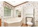 Bright bathroom featuring a large tub, floral wallpaper, and decorative window coverings at 611 W Robinson St, Dallas, NC 28034