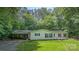 A charming home with green shutters and a covered parking area sits on a well-maintained lawn surrounded by mature trees at 611 W Robinson St, Dallas, NC 28034