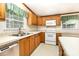 Charming kitchen featuring oak cabinets, white appliances, and a double-bowl sink beneath a window at 611 W Robinson St, Dallas, NC 28034
