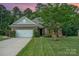 Charming brick home featuring a well-manicured lawn, mature tree, and inviting curb appeal at 8737 Mullis Forest Ct, Mint Hill, NC 28227