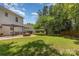 Expansive backyard featuring a brick patio with fire pit and dining area amid mature trees at 9107 Royal Highlands Ct, Charlotte, NC 28277