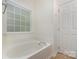 Bathroom featuring a large bathtub with a window and white tiling, creating a calming atmosphere at 9107 Royal Highlands Ct, Charlotte, NC 28277