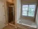Bathroom featuring a bathtub, shower with glass door, and large window at 9593 Camberley Nw Ave, Concord, NC 28027