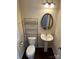Cozy half-bathroom with pedestal sink, oval mirror, and wood look flooring at 9593 Camberley Nw Ave, Concord, NC 28027