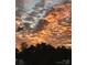 A breathtaking sunset with vibrant clouds over a treeline silhouette at 10016 St Kitts Landing Ln, Charlotte, NC 28278