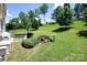 Backyard features a patio with grill, seating, a lush lawn, mature trees, and a bird bath at 10792 Elsfield Nw Ave, Concord, NC 28027