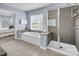 Bathroom showcasing a soaking tub and glass-enclosed shower, adjacent to a bedroom and large window at 10792 Elsfield Nw Ave, Concord, NC 28027