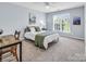Bright bedroom with a large window, comfortable bed with green accents, ceiling fan, and a desk, perfect for relaxing at 10792 Elsfield Nw Ave, Concord, NC 28027