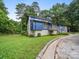 A stylish two-story home with blue accents and gray brickwork is nestled in a lush landscape at 1261 Westbrook Cir, Gastonia, NC 28052