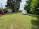 A spacious backyard featuring a well-maintained lawn, multiple sheds, and mature trees at 13427 Homewood Dr, Charlotte, NC 28262