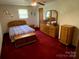 Cozy bedroom features a bed, a dresser with mirror, and wooden furniture at 13427 Homewood Dr, Charlotte, NC 28262