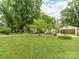 Spacious front yard featuring a well-manicured lawn, mature trees, fenced yard and carport at 138 Shepherd Rd, Mooresville, NC 28115