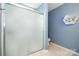 Bathroom featuring a sleek glass-enclosed shower, tiled floors, and blue walls at 16121 Wrights Ferry Rd, Charlotte, NC 28278
