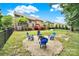 A beautifully landscaped backyard featuring a fire pit with chairs and a spacious lawn for outdoor activities and relaxation at 16714 Hammock Creek Pl, Charlotte, NC 28278