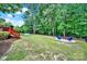 A spacious backyard featuring a fire pit and patio furniture, surrounded by a black iron fence and mature trees at 16714 Hammock Creek Pl, Charlotte, NC 28278