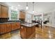 Open-concept kitchen with wood cabinets, granite countertops, an island cooktop, and hardwood floors at 16714 Hammock Creek Pl, Charlotte, NC 28278