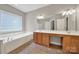 Bright bathroom has double sinks and a jacuzzi tub under a window for plenty of light at 16714 Hammock Creek Pl, Charlotte, NC 28278