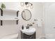 Charming bathroom featuring a pedestal sink, decorative mirror, and shelving at 1734 Seifert Cir, Charlotte, NC 28205